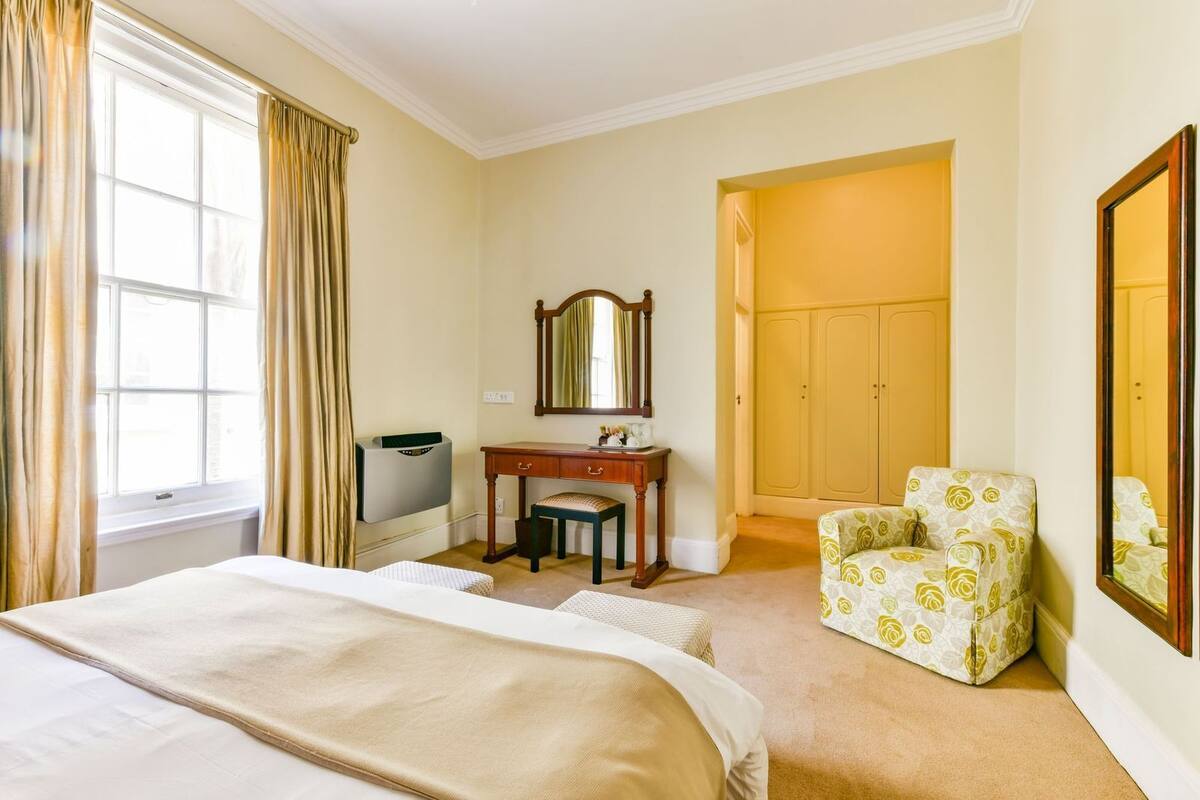 Ein Hotelzimmer mit Bett, Schreibtisch mit Spiegel, Stuhl und Kleiderschrank.