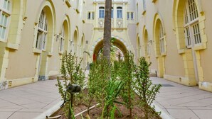 A courtyard with a tall palm tree, surrounded by a building with arched windows and a tiled floor. - King Edward Hotel (Port Elizabeth)