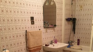 A bathroom with patterned wallpaper, a bidet, a sink, and a mirror.