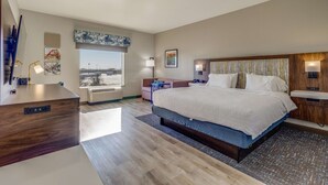 Una habitación de hotel moderna con una cama grande, un escritorio y vistas a la ciudad.