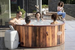 Relax in a hot tub with temperature control, surrounded by a serene outdoor setting and comfortable seating area.