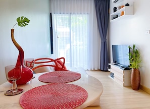 Relax in this stylish living room with a curved table, red placemats, and a green plant.
