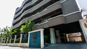 A multi-story building with a gated entrance, a sign indicating it is a serviced apartment complex, and a series of balconies. - Your Private Oasis Stylish 2br With Spacious Living Room and Pool Access (Bangkok)
