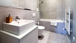 Une salle de bain moderne dotée d’un grand lavabo, de toilettes et d’un espace douche.