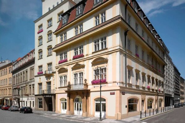 A multi-story building with a classic architectural style, featuring arched windows and balconies with flower boxes.
