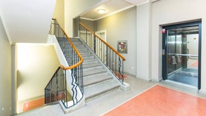 Ein modernes Hotelinnere mit Treppe, Aufzug und einem Teppichbereich in Rot.