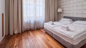 Ein Hotelzimmer mit einem großen Bett, Holzboden und leichten Vorhängen.