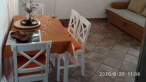 Een eetruimte met een tafel, stoelen, een televisie en een kalender aan de muur.