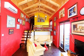 Una habitación acogedora con techo de madera, un sofá, una mesa de comedor y un televisor.