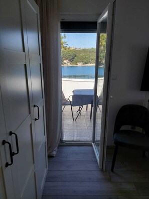 Une piĂšce dotĂ©e dâune porte coulissante donnant sur un espace extĂ©rieur amĂ©nagĂ© avec une table et des chaises, offrant une vue sur un plan dâeau, et comprenant Ă©galement une chaise Ă lâintĂ©rieur de la piĂšce.