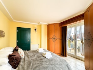 Une chambre à coucher avec un lit, une porte verte, une fenêtre avec des rideaux et une vue sur l’extérieur.