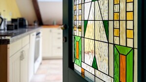 A kitchen with a window and a door with a geometric stained glass design.