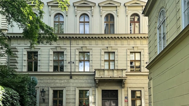 A multi-story building with a symmetrical facade, large windows, and a central entrance with a decorative door.