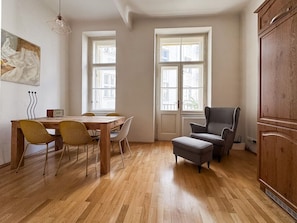 A room with a wooden floor, a dining table with chairs, a grey armchair, and a cabinet. - The BEST place in Prague - Old Town (Prague 1)