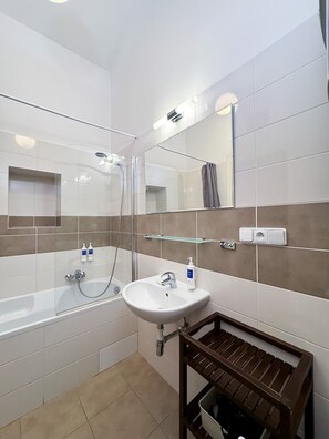 A modern bathroom with a bathtub, a sink, a mirror, and a shower.