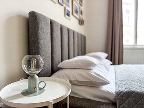 A hotel room with a bed, a bedside table with a lamp, and a window with curtains.
