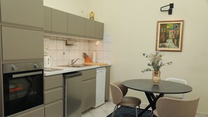Una cucina compatta con elettrodomestici moderni, un'area pranzo con due sedie e un vaso di fiori sul tavolo.