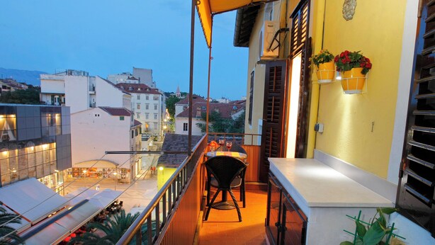 Un balcone con vista sulla città, un tavolo con sedie e piante in vaso.