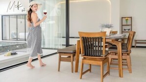 A modern interior with a dining area featuring wooden furniture and a glass wall with a view. - Skyline Resort (Bang Phli)