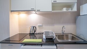Une cuisine moderne équipée d’une cuisinière intégrée, d’une bouilloire, d’une machine à café, d’un évier et d’un lave-vaisselle.