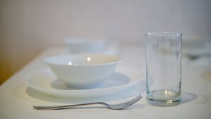 Une table à manger avec une assiette blanche, un bol, un verre et une fourchette.