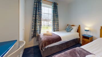 A hotel room with two beds, a desk, and a window with curtains.