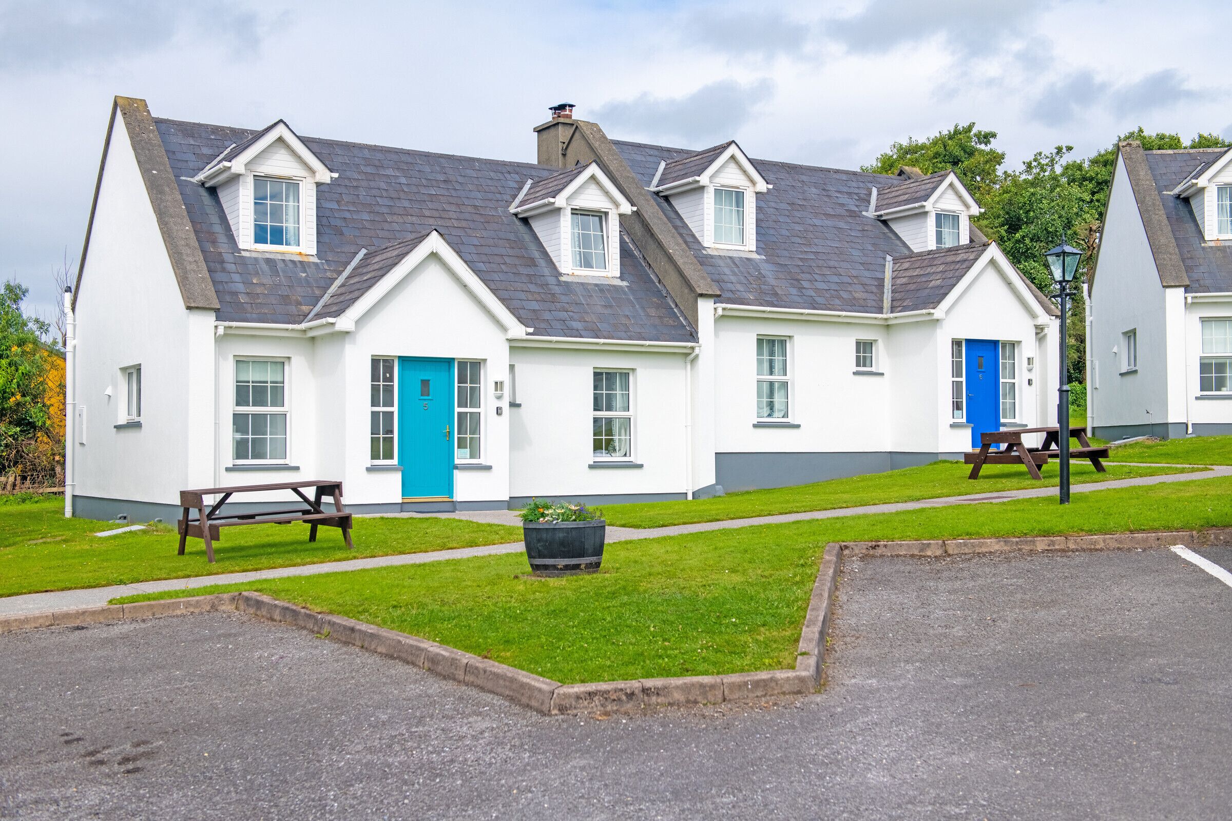 A row of white buildings with blue doors and a picnic table in the foreground.