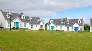 A row of white cottages with blue and red doors, each with a picnic table in front.