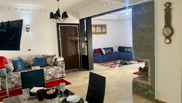 Una sala moderna con comedor, un conjunto de sofás, una araña y una chimenea.