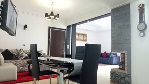 Una sala de estar con sofá, una mesa de comedor con sillas, una chimenea y una puerta que da a otra habitación.