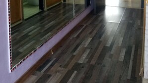 Un pasillo con un espejo grande, suelo de madera y una puerta que da a un baño.