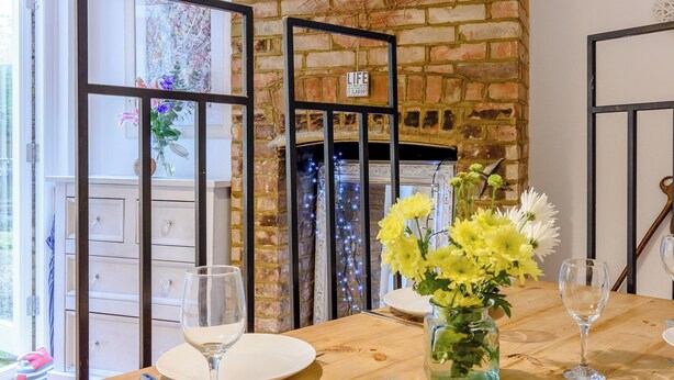 Una mesa de comedor con platos, vasos y un jarrón de flores.