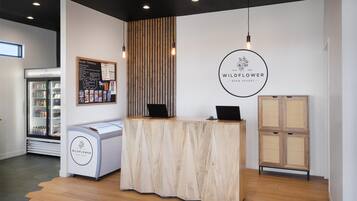 A reception desk with a wooden finish, a refrigerator with beverages, and a menu board on the wall.