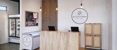 A reception desk with a wooden finish, a refrigerator with beverages, and a menu board on the wall.