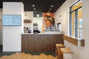 A modern cafe interior with a wooden counter, menu board, and seating area.