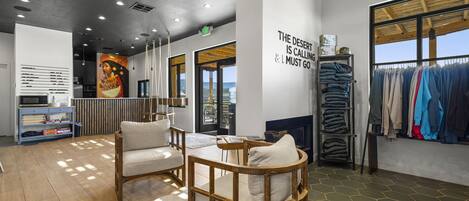 A modern interior with a seating area, a clothing rack, and a wall with motivational text.