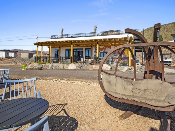 A building with a covered patio area, outdoor seating, and a unique metal swing structure.