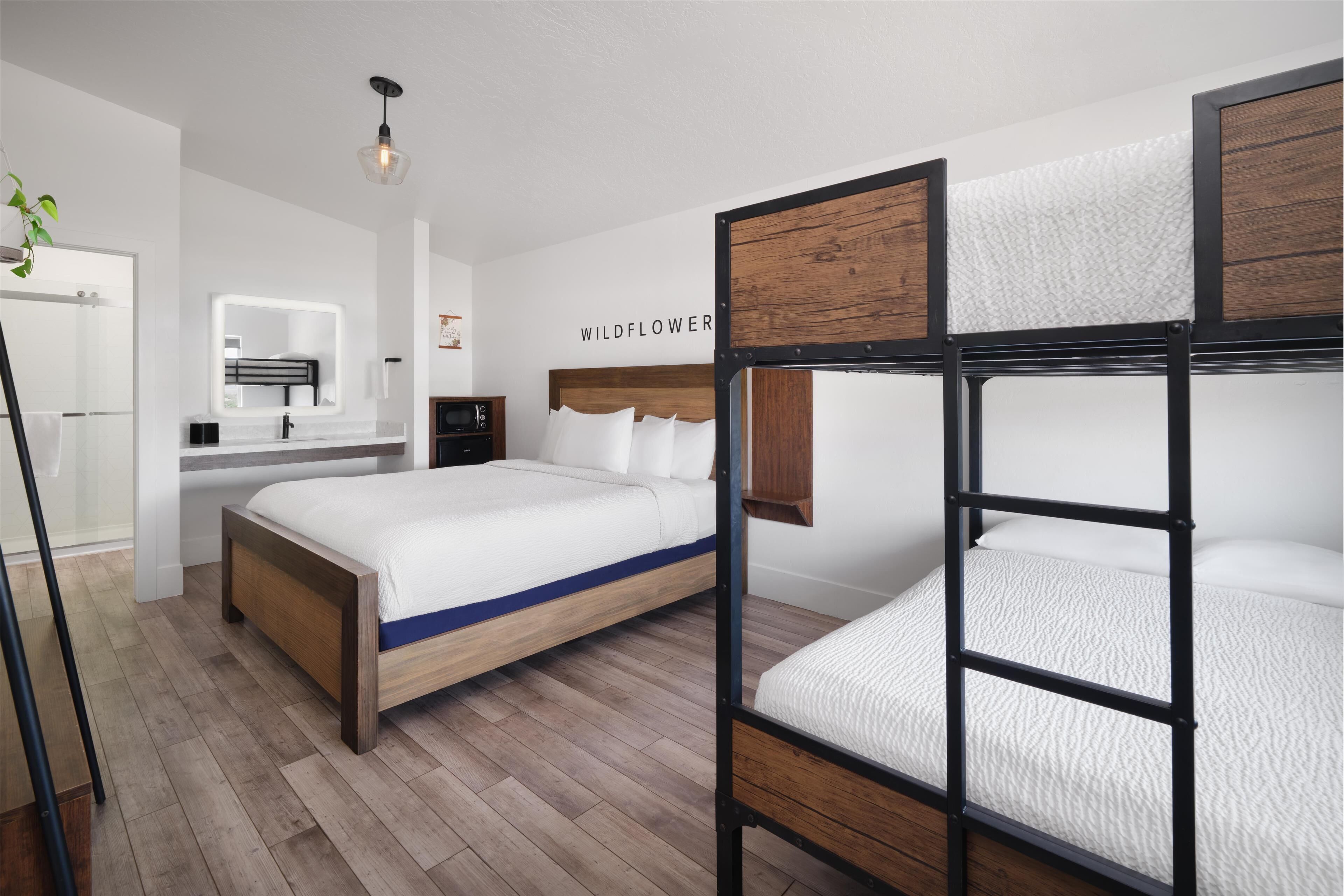 A modern bedroom with a bunk bed, a wooden floor, a bedside table, and a mirror.