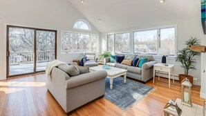 A spacious living room with a high ceiling, large windows, and a view of the outdoors. - Family retreat: 5 min walk to Bayview Beach, sleeps 10 (Dennis)