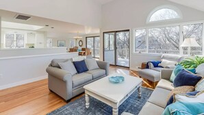 A spacious living room with a grey sofa, a white coffee table, and a large window offering a view of the outdoors. - Family retreat: 5 min walk to Bayview Beach, sleeps 10 (Dennis)
