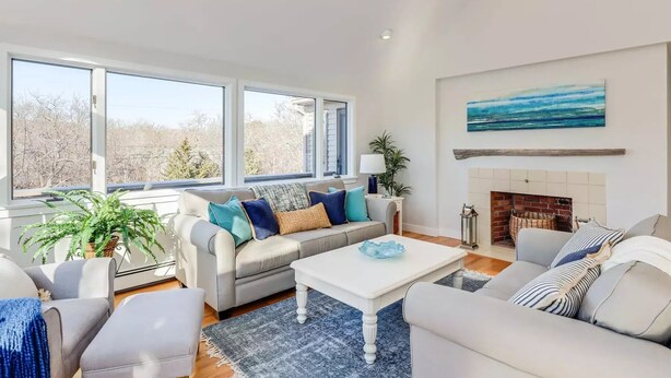 A spacious living room with a fireplace, large windows, and a view of the outdoors. - Family retreat: 5 min walk to Bayview Beach, sleeps 10 (Dennis)