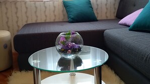 A living room with a glass table, a sofa, and a decorative glass bowl with flowers. - New And Completely Renovated Apartment 5-1 (Marina)
