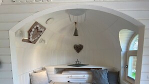 A cozy room with a sloped ceiling, a heart-shaped decoration, a small table, and a window. - Iglu Camp Heidewald (Sassenberg)