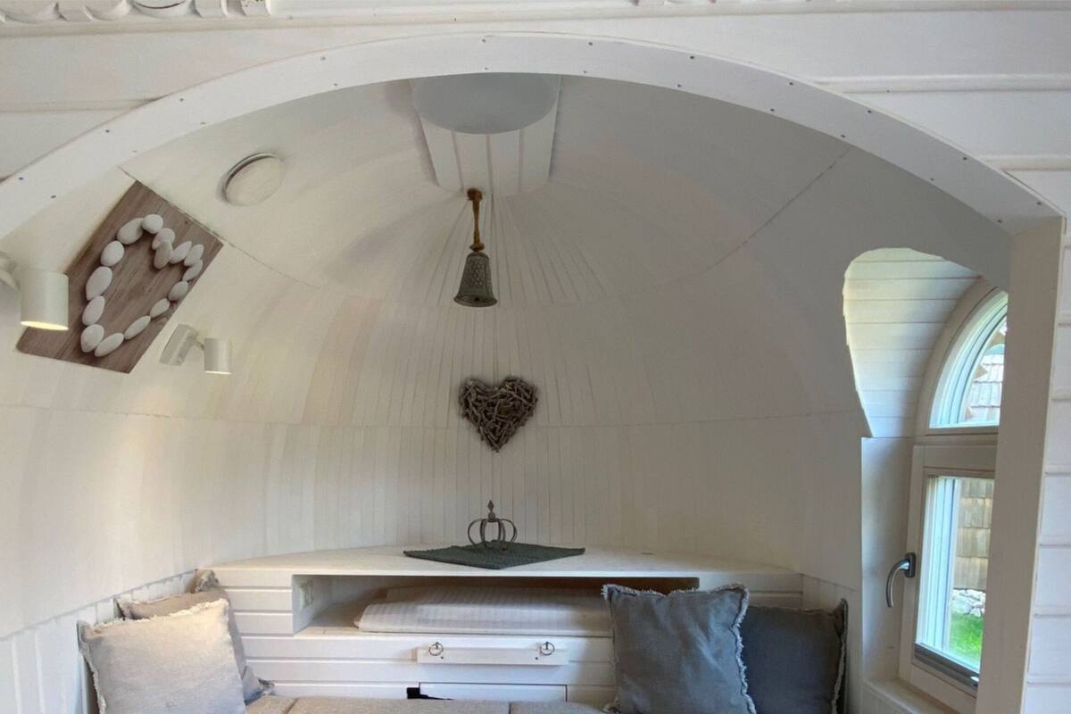 Um quarto aconchegante com teto inclinado, uma decoração em formato de coração, uma mesa pequena e uma janela.