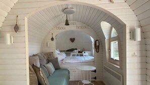 A cozy, arched room with a bed, a small table, and a window. - Iglu Camp Heidewald (Sassenberg)