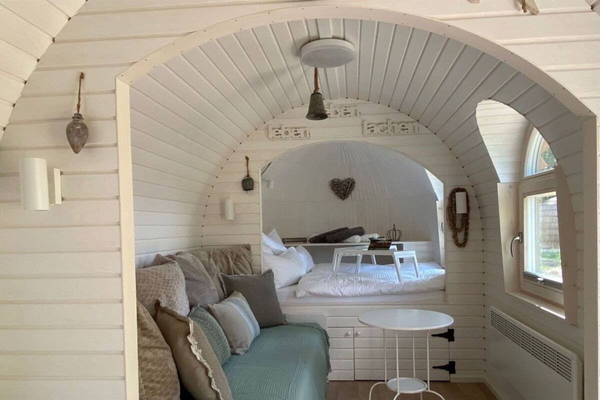 Um quarto aconchegante com arco, uma cama, uma mesa pequena e uma janela.