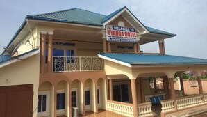 A hotel with a signboard reading "Welcome to Nyaboda Hotel," indicating it offers a bar, restaurant, and conference hall. - Nyaboa Hotel (Kumasi)