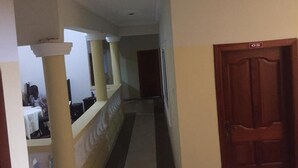 A hallway with a wooden door marked "05" and a staircase with a white railing. - Nyaboa Hotel (Kumasi)