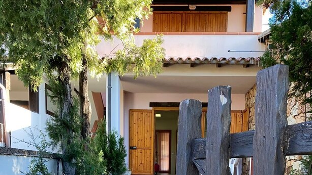 A stone pathway leading to a building with a wooden gate. - Appartamento Rosa La Cinta (San Teodoro)