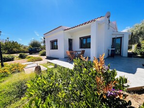 Une maison moderne dotée d’un patio, d’un coin repas et d’un jardin.